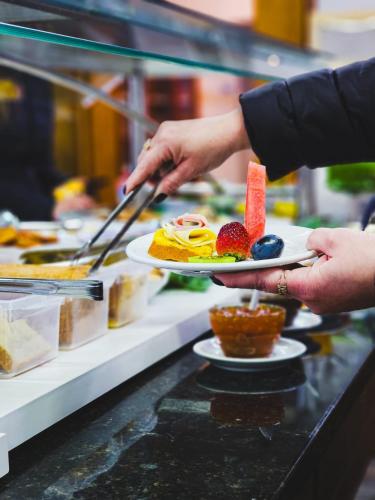 a person holding a plate of food on a buffet at DM Thermas Hotel Irai in Iraí