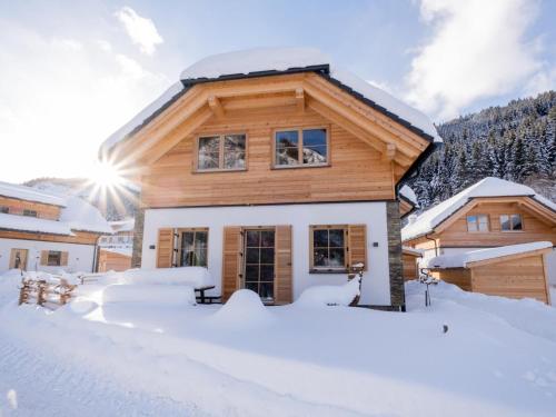 a house covered in snow with the sun in the background at Donnersbach Lodge in Donnersbachwald