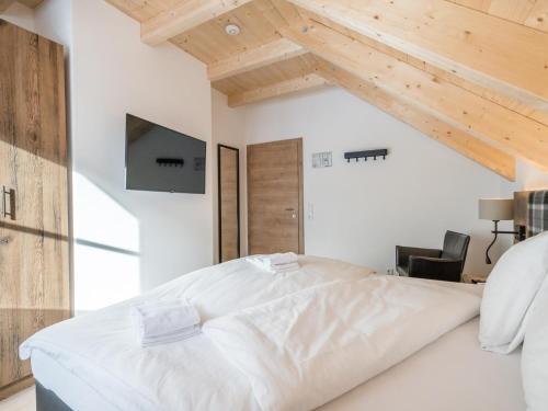 a bedroom with a large white bed and wooden ceilings at Donnersbach Lodge in Donnersbachwald