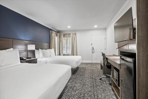 a hotel room with two beds and a television at University Park Inn & Suites, an Ascend Collection Hotel in Davis