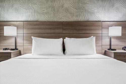 a white bed with two pillows and two lamps at University Park Inn & Suites, an Ascend Collection Hotel in Davis
