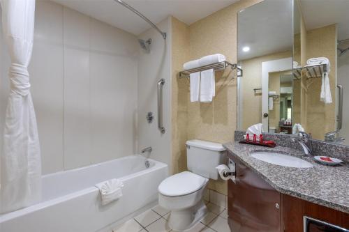 a bathroom with a toilet and a tub and a sink at SureStay Plus Hotel by Best Western Chicago Lombard in Lombard