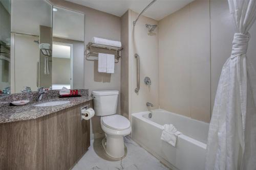a bathroom with a toilet and a tub and a sink at SureStay Plus Hotel by Best Western Chicago Lombard in Lombard