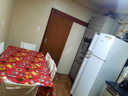 a kitchen with a table and a refrigerator in a room at Apartamento térreo fundos in Torres