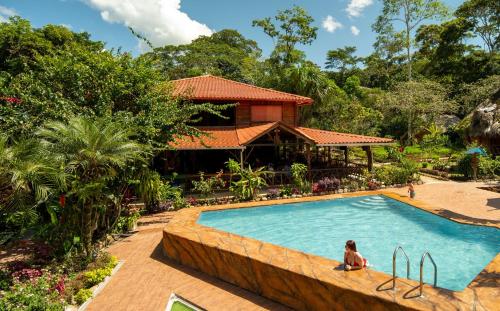 a woman sitting in a pool in front of a house at Suchipakari Amazon Eco -Lodge & Jungle Reserve in Puerto Misahuallí