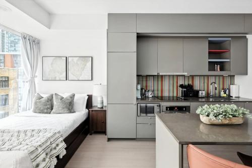 ein weißes Schlafzimmer mit Bett und Küche in der Unterkunft Modern Studio Retreat in Downtown Toronto in Toronto