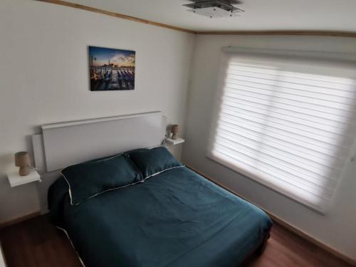 1 dormitorio con 1 cama verde y 2 ventanas en Cabaña Osorno en pleno campo, en Osorno