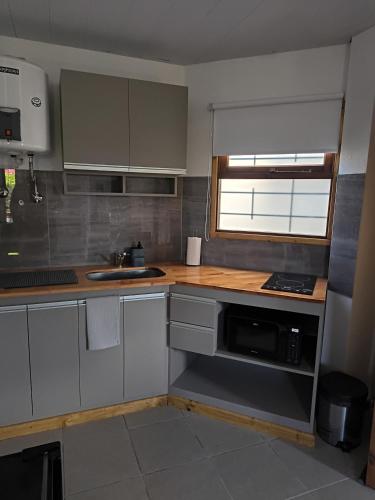 Una cocina con gabinetes blancos, un fregadero y un microondas. en El Molino Sur, en Mar del Plata