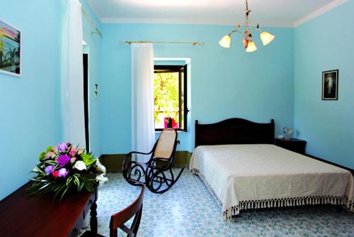 um quarto azul com uma cama e uma mesa com flores em Il Nibbio Reale Country House em Rocca dʼEvandro