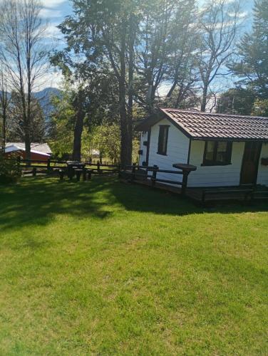 a white house with a picnic table in the grass at Cabañas Wualmapu " acceso sólo vehiculos tipo camioneta, jeep o SUV" in Pucón