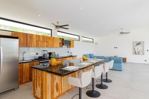 a kitchen with a bar with white chairs and a blue couch at Villas Roma Del Mar in Playa Naranjo