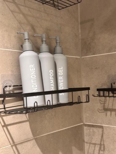 three white bottles on a shelf in a shower at Cozy one Bedroom with Views In Birmingham City Center in Birmingham