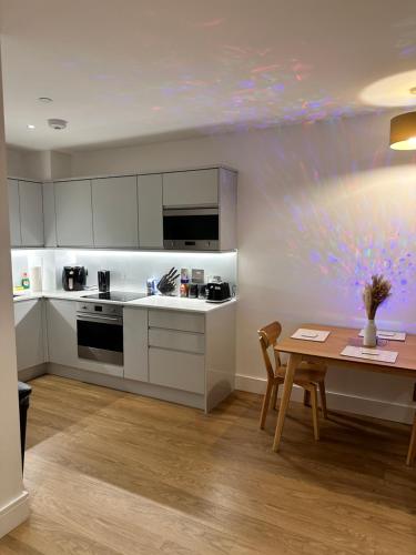 a kitchen with white cabinets and a wooden table at Cozy one Bedroom with Views In Birmingham City Center in Birmingham