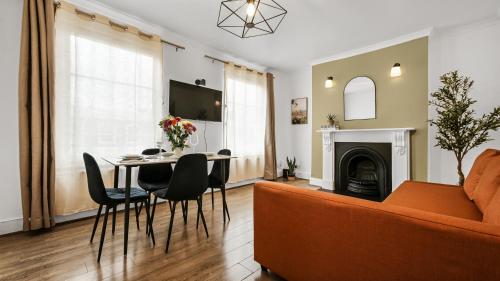 a living room with a couch and a table at Lovely Flat by Emirates - 5 mins to Kings Cross St Pancras in London