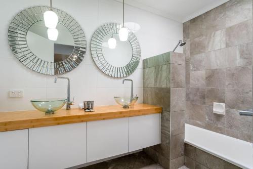 a bathroom with two sinks and two mirrors at Kangaroo Point Oasis Getaway Spacious and modern in Brisbane