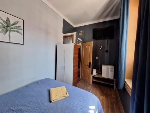 a bedroom with a blue bed and a refrigerator at lindisimo casona hostal en el centro de santiago in Santiago