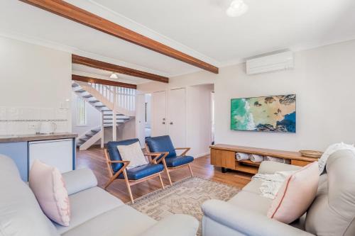 a living room with a white couch and blue chairs at Banksia on Ocean in Evans Head