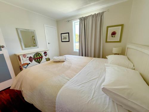 a large white bed in a bedroom with a window at 'Noni's House' Coastal Opononi Hokianga in Opononi