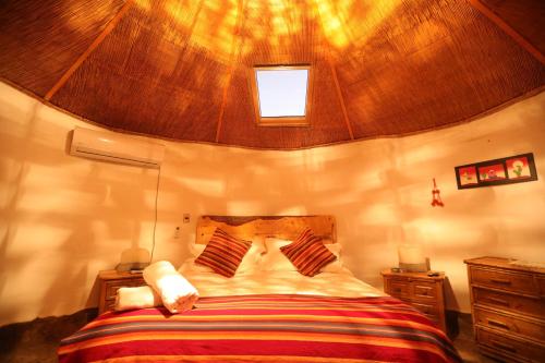 a bedroom with a large bed with a wooden ceiling at Bangalô Ayllu Atacama in San Pedro de Atacama