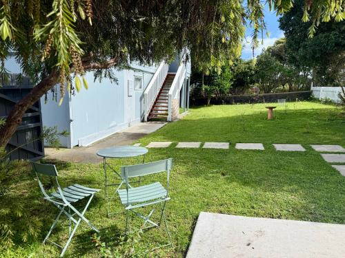 two chairs and a table in a yard at 'Noni's House' Coastal Opononi Hokianga in Opononi