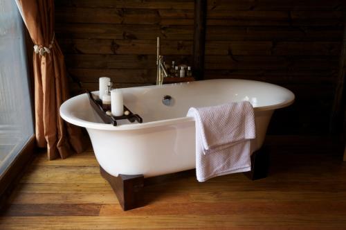 Mkalinzu的住宿－Serena Mivumo River Lodge，浴室铺有木地板,配有白色浴缸。