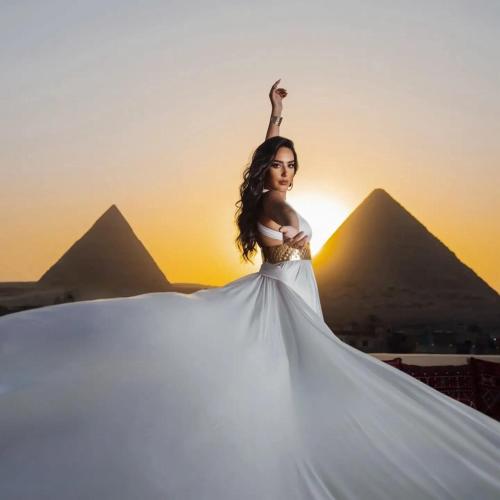 カイロにあるgrand Golden Pyramids viewのピラミッドの前でポーズをとるドレスを着た女性