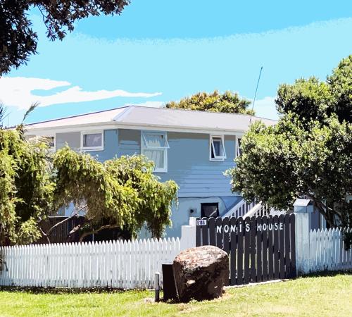 a blue house with a fence and a sign at 'Noni's House' Coastal Opononi Hokianga in Opononi
