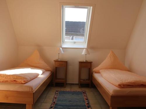 two twin beds in a room with a window at One-bedroom apartment in Borkum