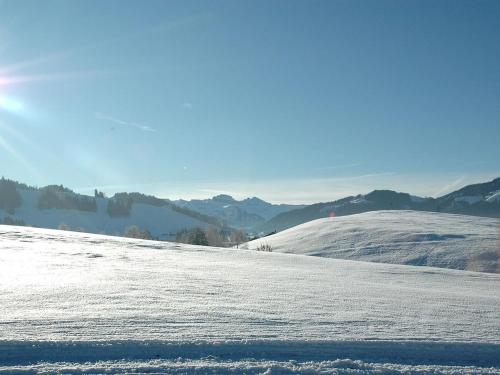 a snow covered slope with mountains in the background at Holiday farm by the lake in Etzel