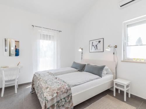 a white bedroom with a bed and a table at 1-bedroom holiday home in Nova Vas