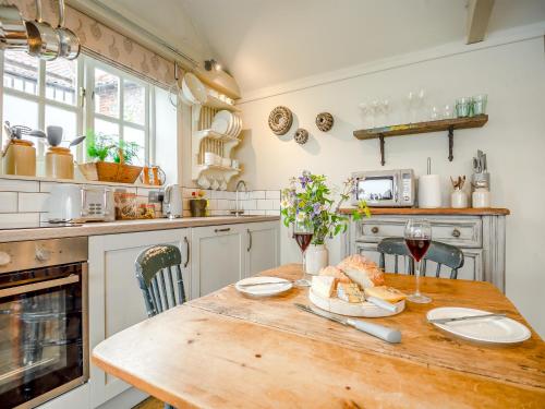 a kitchen with a wooden table with glasses of wine at The Old Candle Shop in Little Walsingham