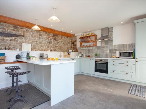 una cucina con armadi bianchi e un muro in pietra di The Woodshed a Sheepwash