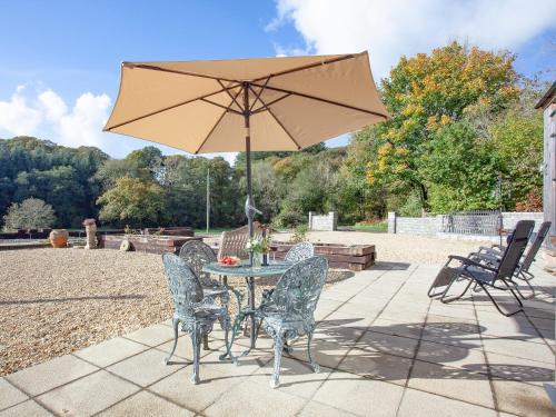 un tavolo con sedie e un ombrellone in un patio di The Woodshed a Sheepwash