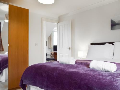 a bedroom with a bed with a purple blanket at Renwood in Eynsham