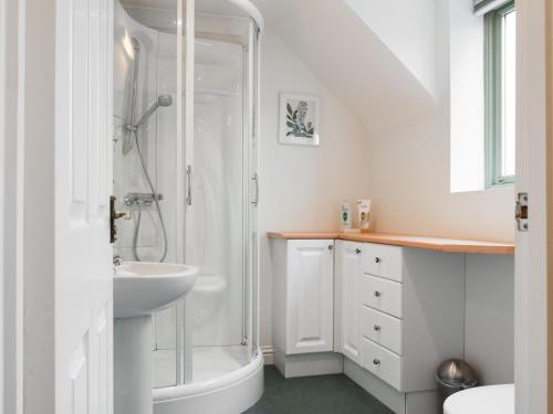 a white bathroom with a shower and a sink at Renwood in Eynsham