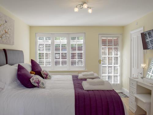 a bedroom with a large white bed with purple pillows at The Coach House in Wootton Bridge