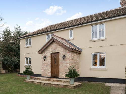 a white house with a brown door at Wisteria House in Henstead