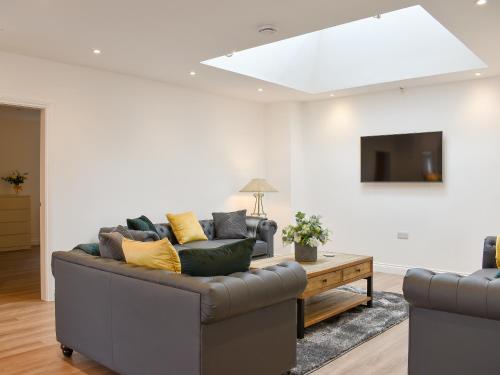 een woonkamer met een bank en een tv bij Redstones Cottage in Greasby