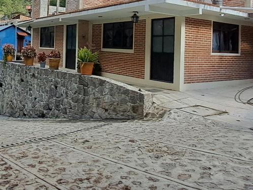 a house with a stone retaining wall in front of it at Cabaña La Hacienda 1 in Mineral del Chico