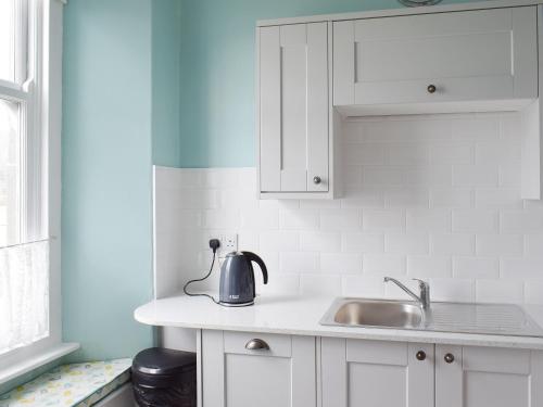 a kitchen with white cabinets and a tea kettle on a sink at Mere View in Ambleside