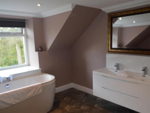 a bathroom with a sink and a tub and a mirror at Farmhouse in Dunragit