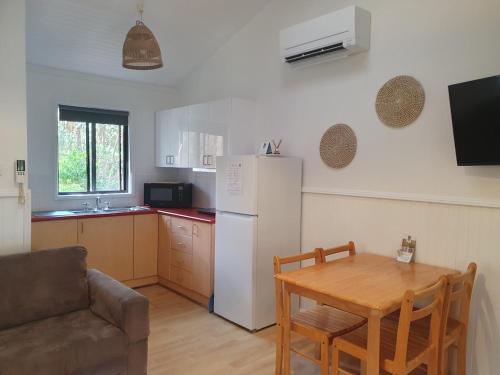 a kitchen with a table and a white refrigerator at Wanderers Retreat in Nelson Bay