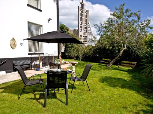 a patio with a table and chairs and an umbrella at Devon Villa Garden Apartment in Torquay