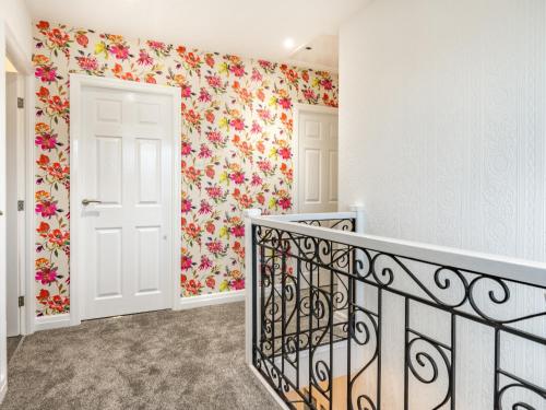 a hallway with a staircase with floral wallpaper at The Gables in Sewerby