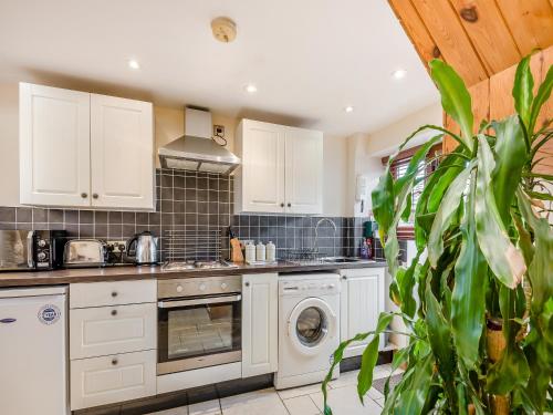 a kitchen with white cabinets and a washer and dryer at The Stables in Bream