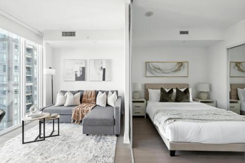 a white bedroom with a bed and a couch at Stylish 1BR Condo in the heart of the Downtown TO in Toronto