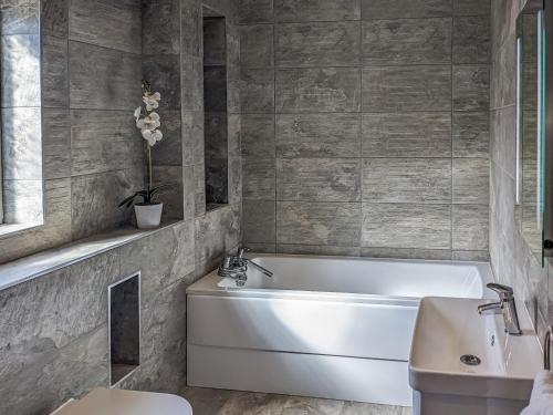 a bathroom with a white tub and a sink at Hogbert's Hideaway in Carlton Colville