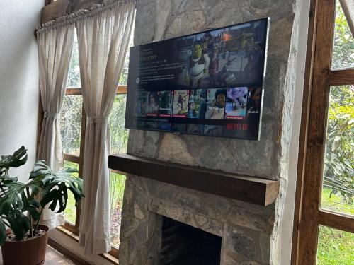 サカトランにあるCabaña Ixachiの窓のある部屋の石造りの暖炉の上に置かれたテレビ