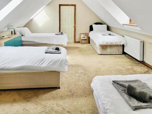 a attic bedroom with three beds and a staircase at Grantham House in Grantham