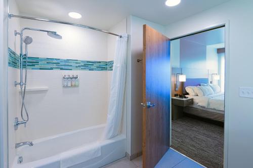 a bathroom with a shower and a tub and a bed at EVEN Hotels Rochester - Mayo Clinic Area by IHG in Rochester